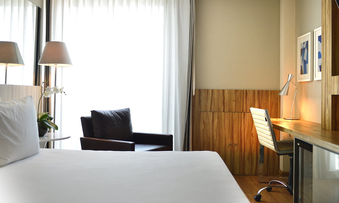 O Twin Standard do Pestana Rio Atlântica tem uma cama de casal, uma poltrona e uma secretária com cadeira confortável