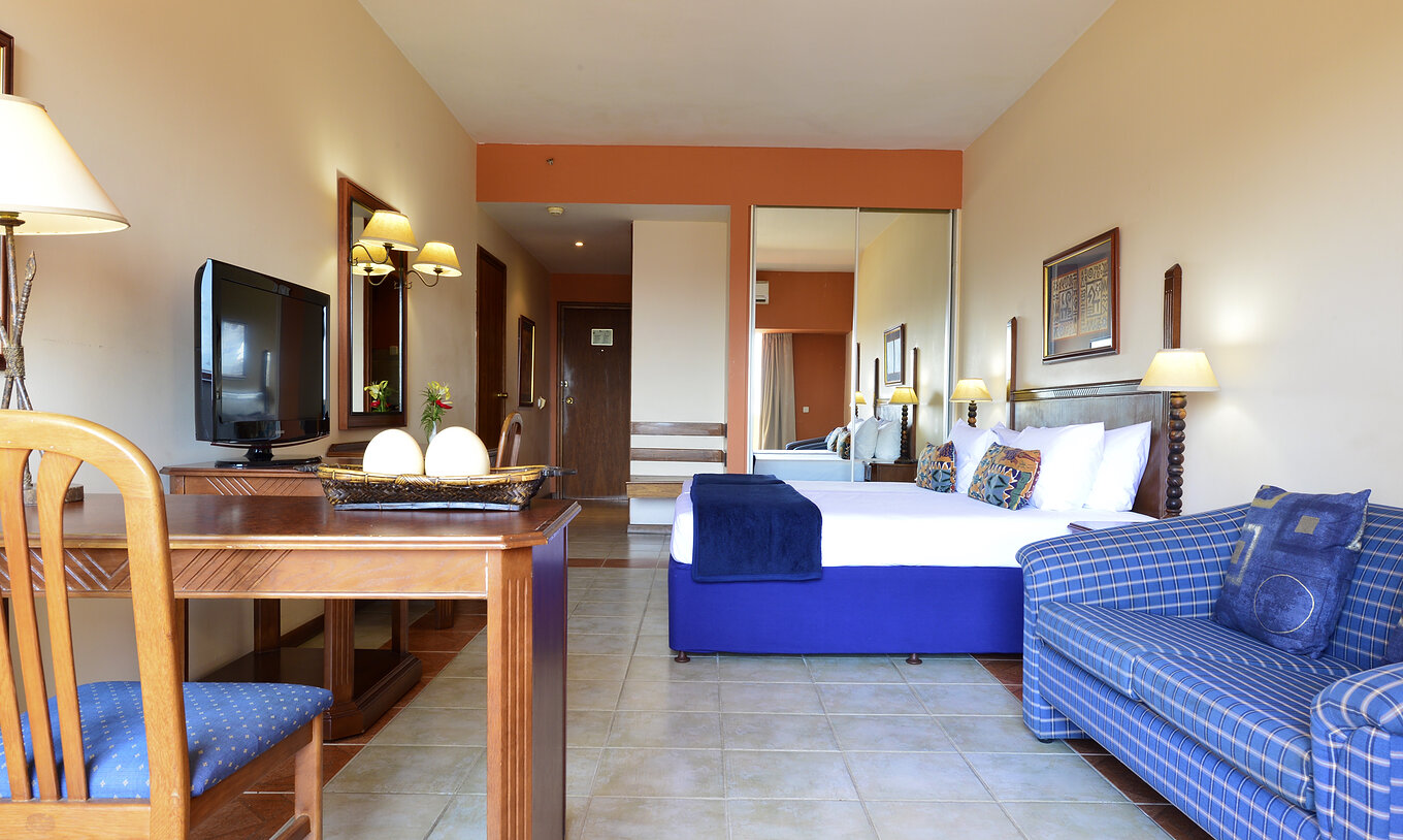 A Suite Executiva Familiar do Pestana Rovuma tem uma cama de casal, um armário com espelho, uma televisão e um sofá