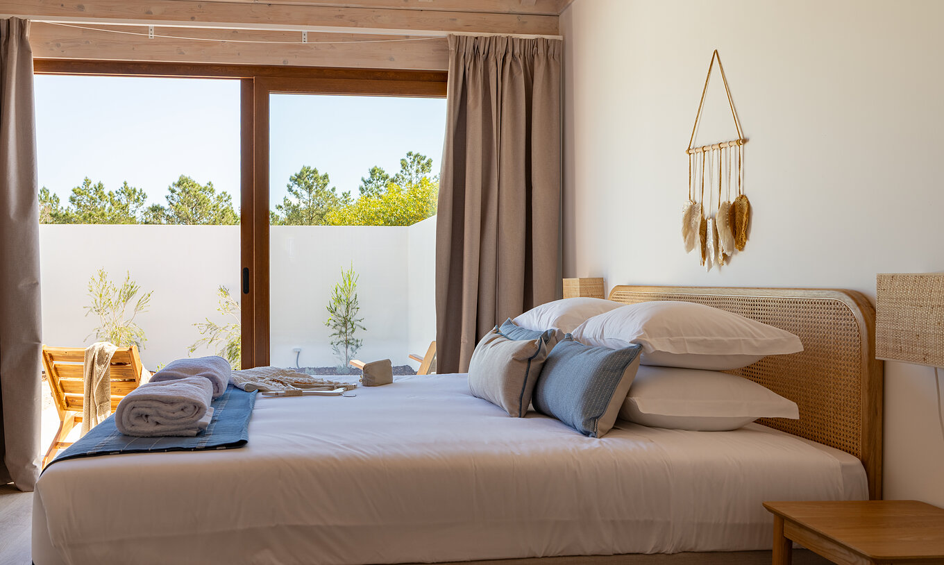 A Premium Green Villa do Pestana Comporta Village Residences tem um quarto com uma cama de casal e uma grande janela 