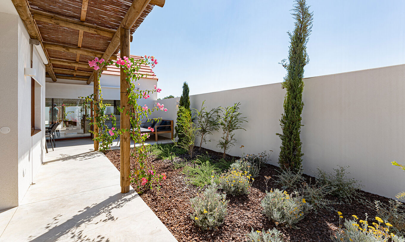 A Standard Green Villa do Pestana Comporta Village Residences tem um jardim com plantas e uma pérgola de madeira