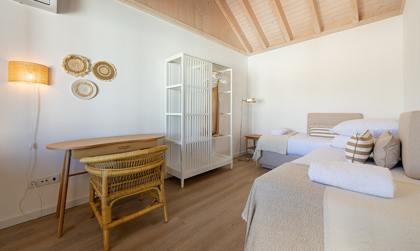 A Standard Villa do Pestana Comporta Village Residences tem um quarto com cama, uma mesa e uma cadeira de vime