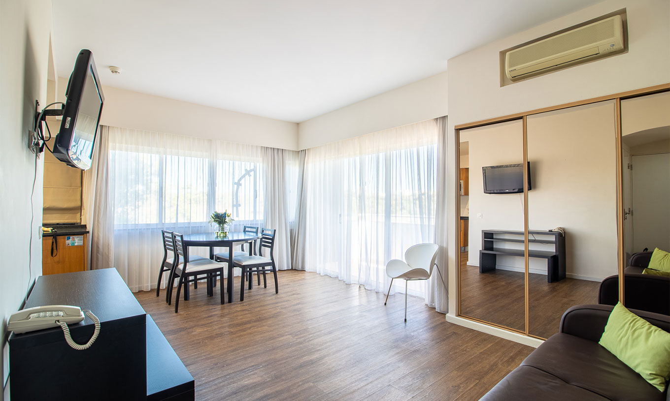 O Apartamento T1 Vista Jardim do Pestana Alvor Atlântico tem um sofá com televisão e um armário com espelho