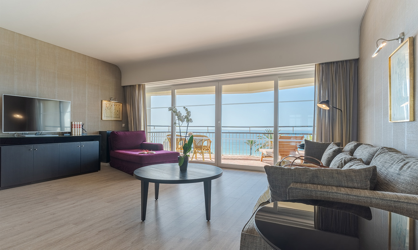 A Suite Luxo Vista Mar do Pestana Alvor Praia tem uma sala com sofá, poltrona, mesa, televisão e varanda com vista mar