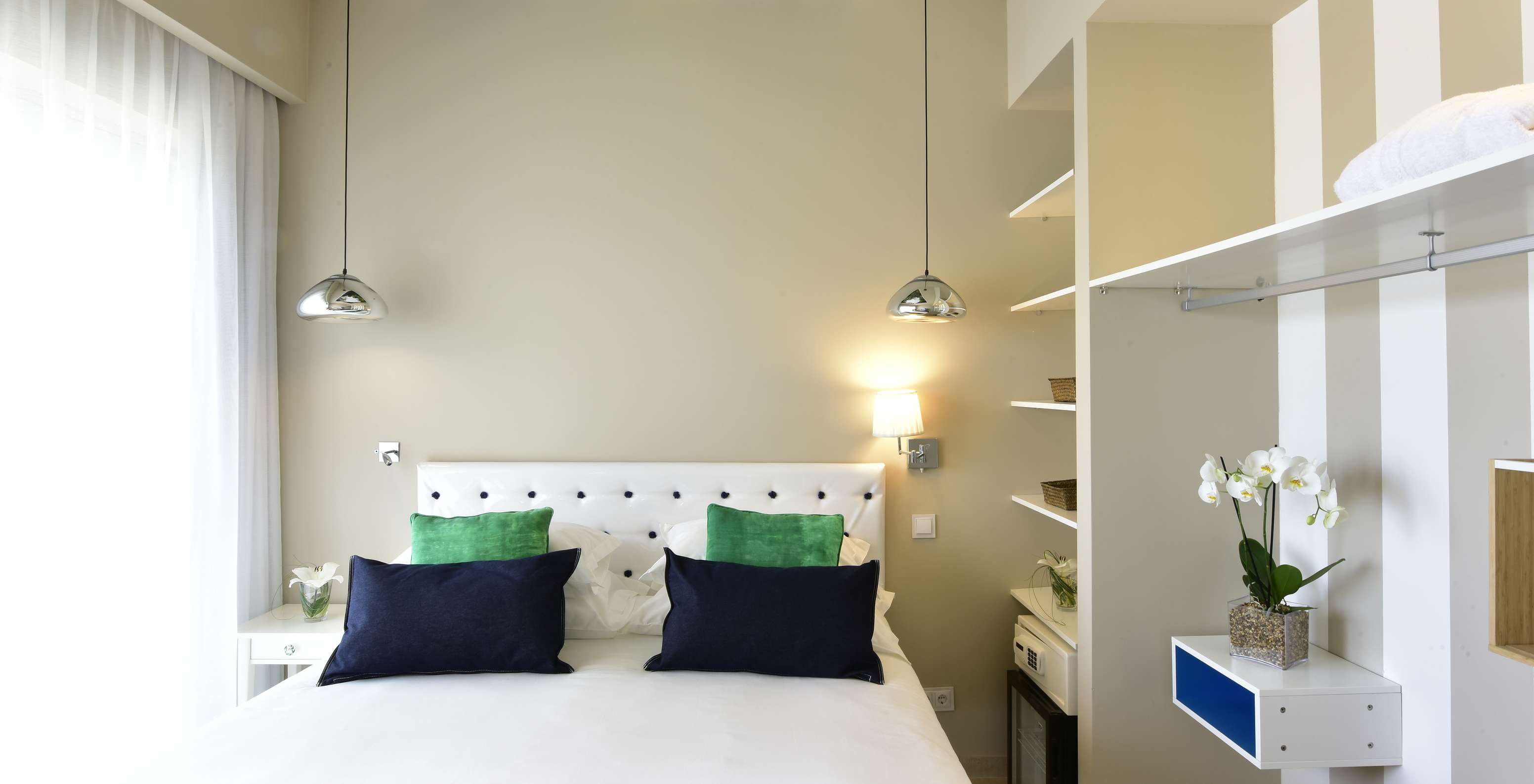 A Suite do Pestana Alvor South Beach tem uma cama de casal com a janela de um lado e um armário aberto com minibar do outro