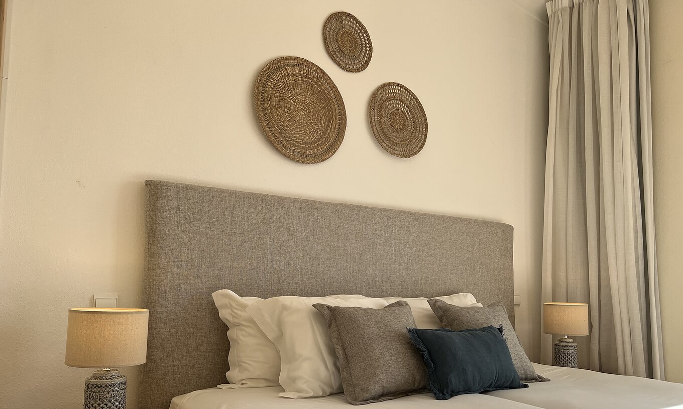 O Apartamento T1 Standard do Pestana Palm Gardens tem uma cama de casal com almofadas decorativas e quadros decorativos