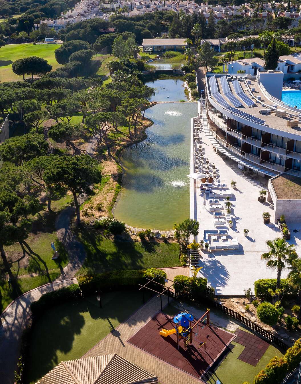 Vista do Pestana Vila Sol - Vilamoura, um hotel 5 estrelas em Vilamoura com piscina e rodeado de um lago e vegetação verde
