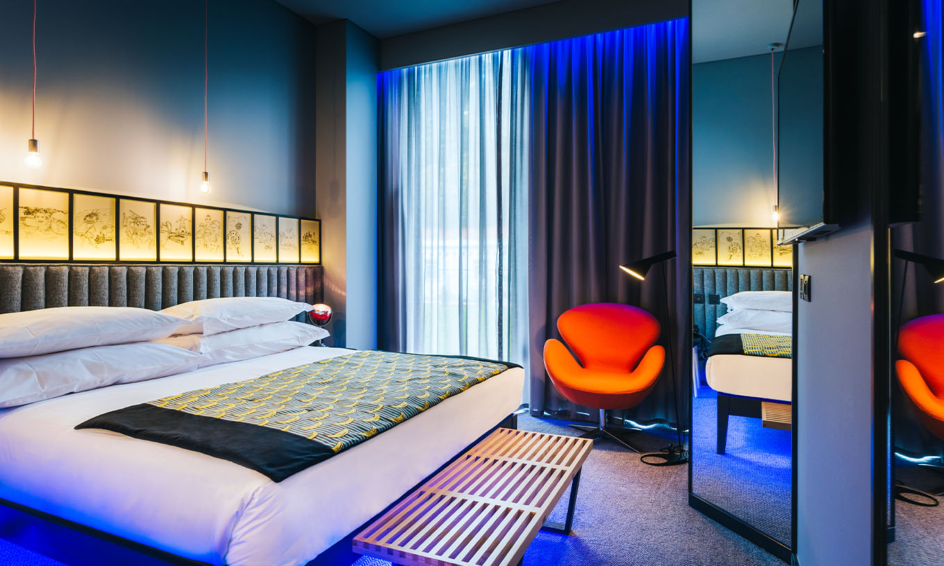 O Quarto CR7 do Pestana CR7 Funchal tem um espaço amplo com uma cama de casal, um banco de apoio e uma cadeira confortável