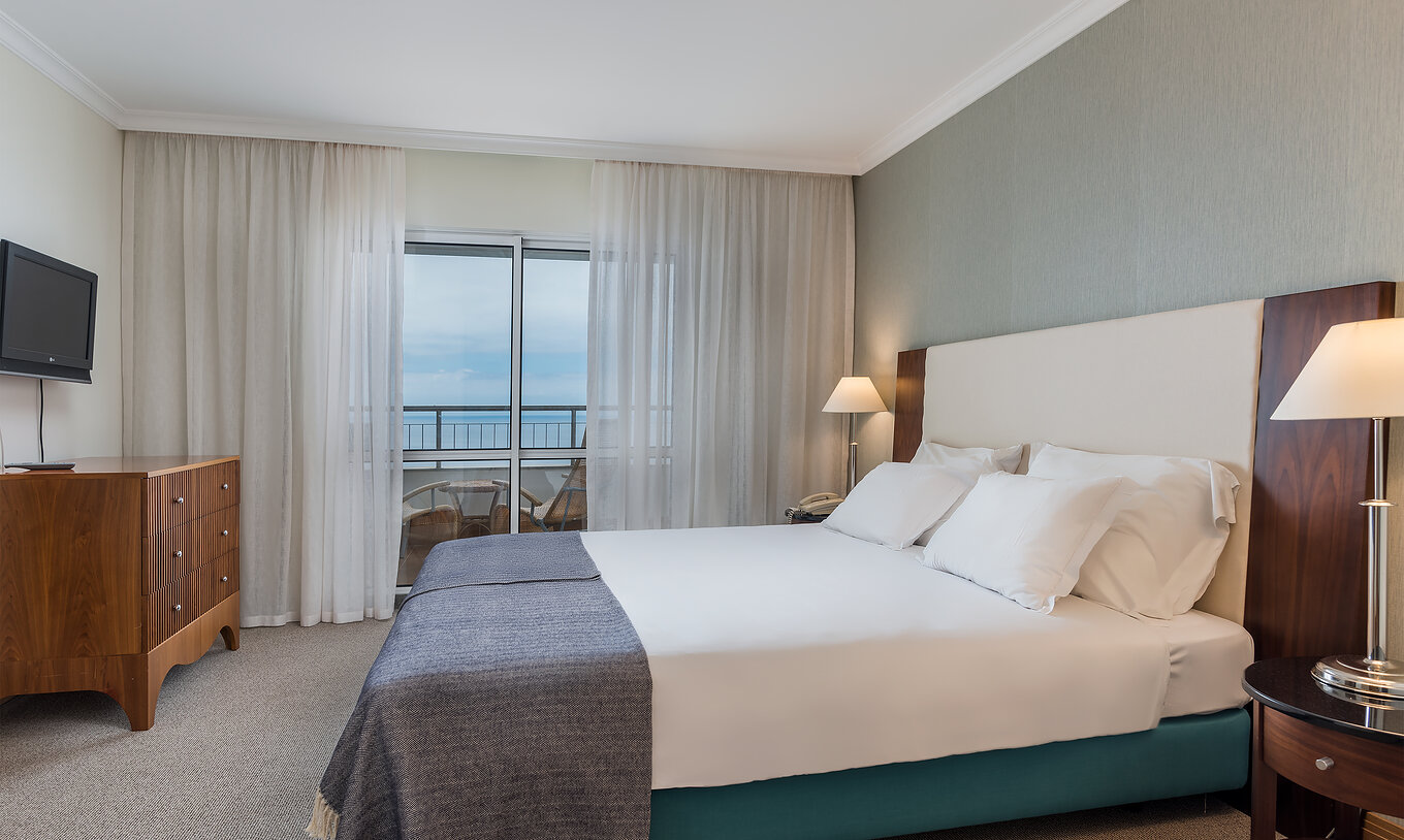O quarto Clássico Vista Mar do Pestana Grand tem uma cama de casal com televisão e vista para o mar