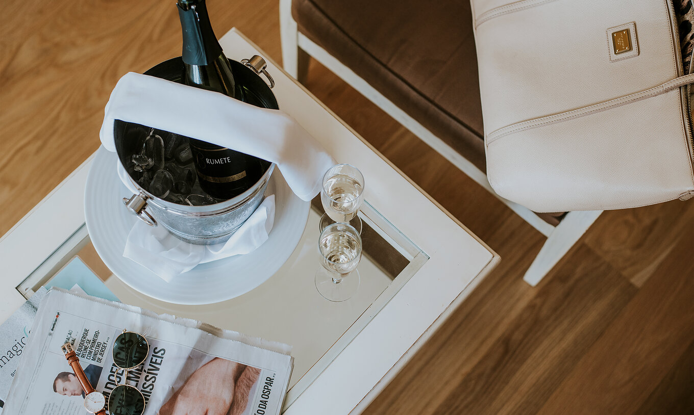 O Apartamento T2 do Pestana Madeira Beach Club tem uma mesa com champagne em gelo, jornais e uma cadeira