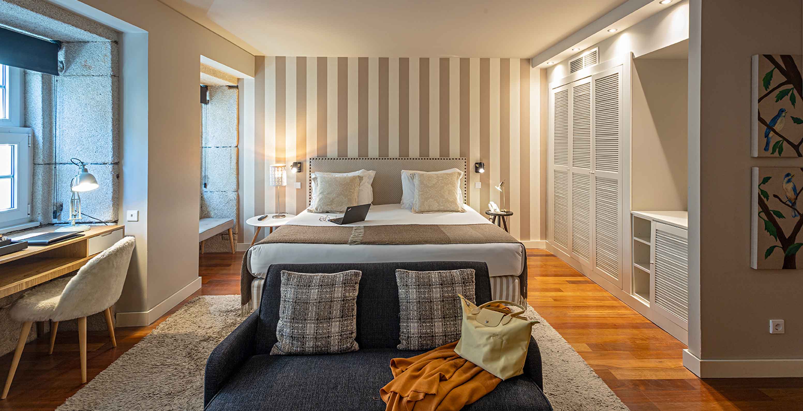 A Heritage Suite do Pestana Vintage Porto tem uma cama de casal, um sofá, uma secretária e um roupeiro branco