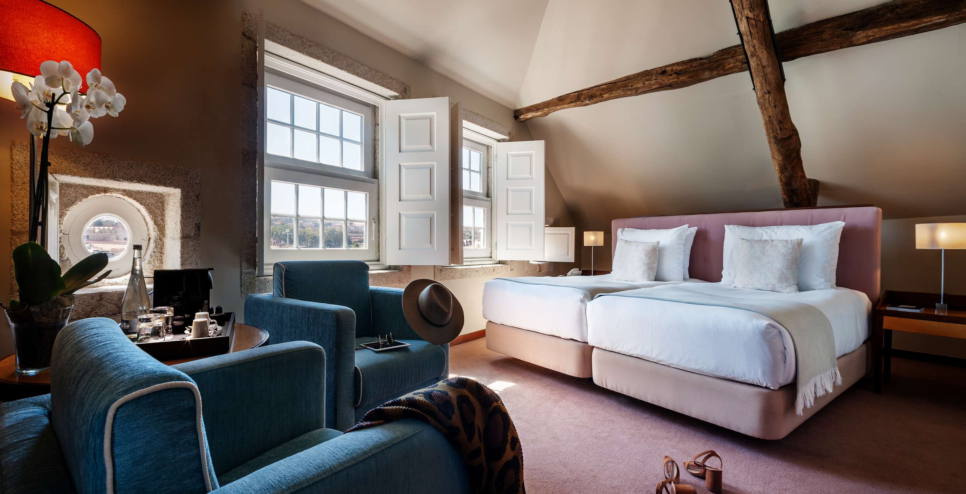 O Plaza do Pestana Vintage Porto tem duas camas, dois cadeirões, um tronco de madeira no teto e duas janelas grandes