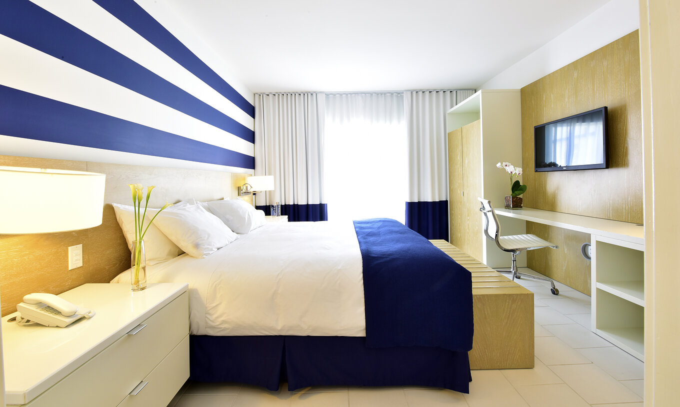 O Suite King com Varanda do Pestana Miami South Beach é um quarto moderno com cama grande e decoração azul e branca
