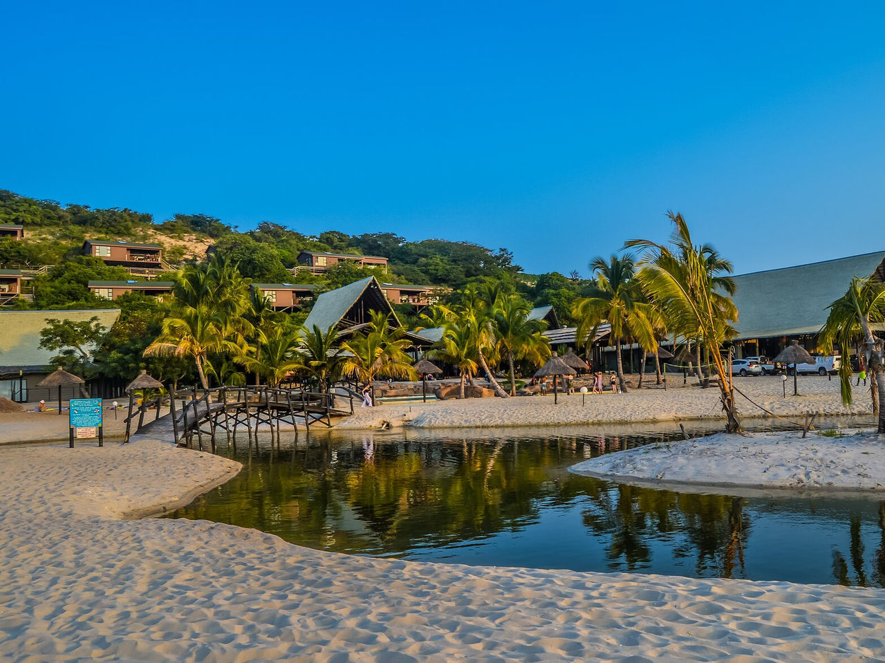 Strand in Maputo mit einem Fluss durch den Sand, Brücke zum Überqueren, verstreute Palmen