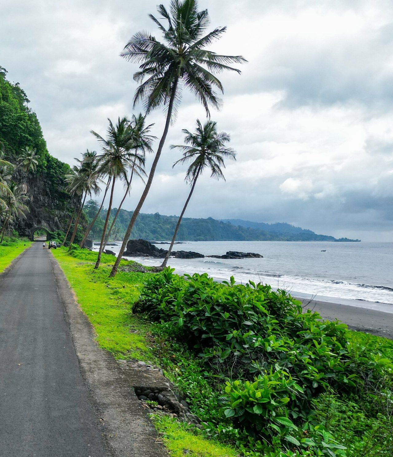 Blick auf eine Asphaltstraße in São Tomé und Príncipe, am Meer, mit Vegetation ringsum