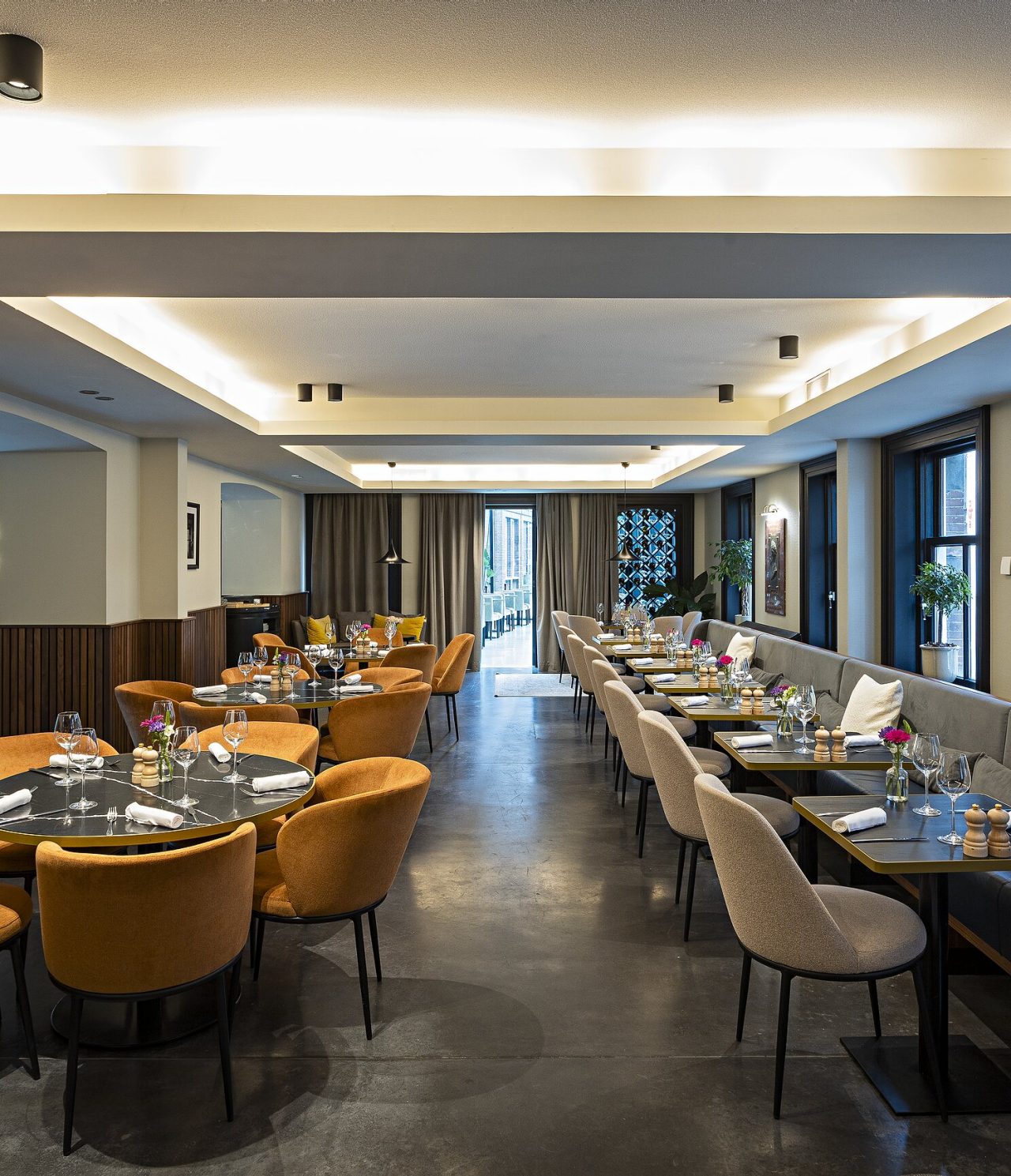 Das Restaurant Archive im 5-Sterne-Hotel in Amsterdam hat einen großen Raum mit runden und quadratischen Tischen und Stühlen