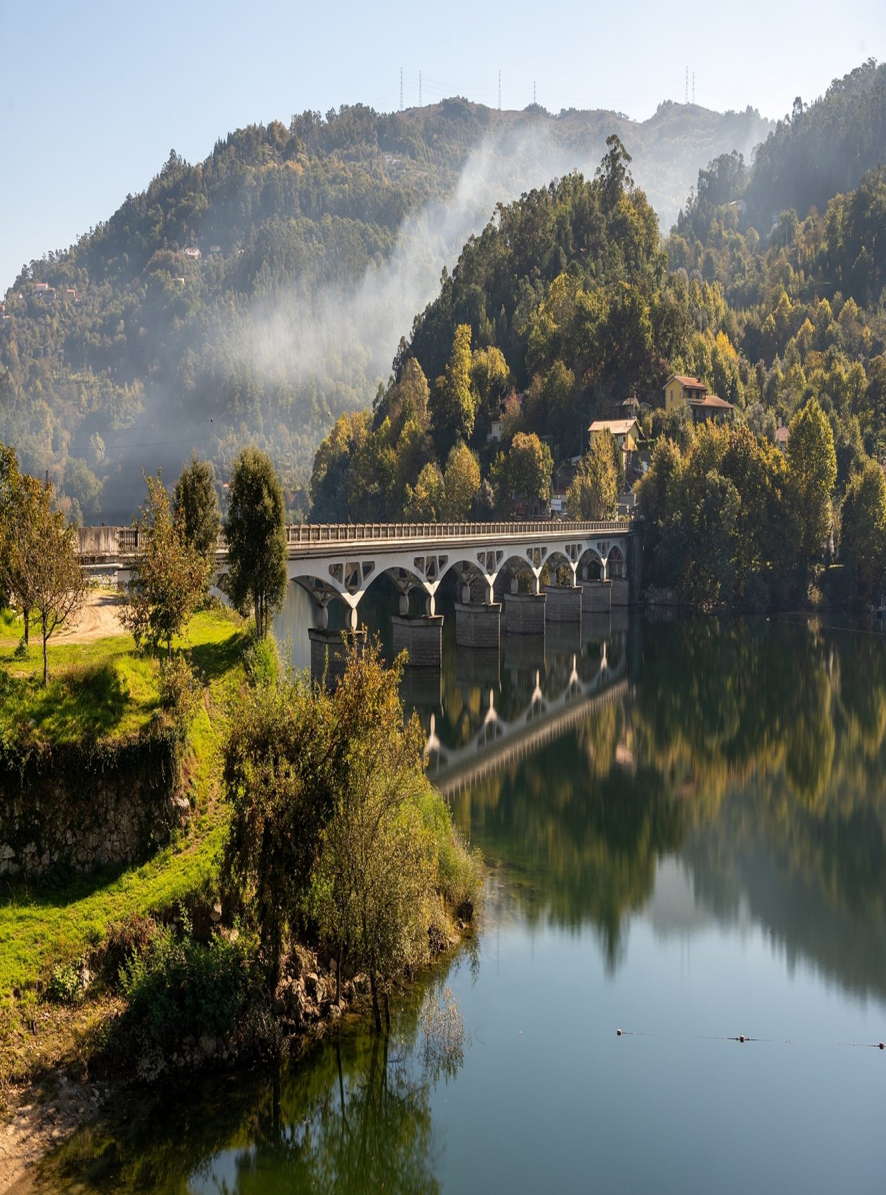 Landschaft im Norden Portugals mit einer Steinbrücke über einen Fluss, umgeben von grünen Hügeln
