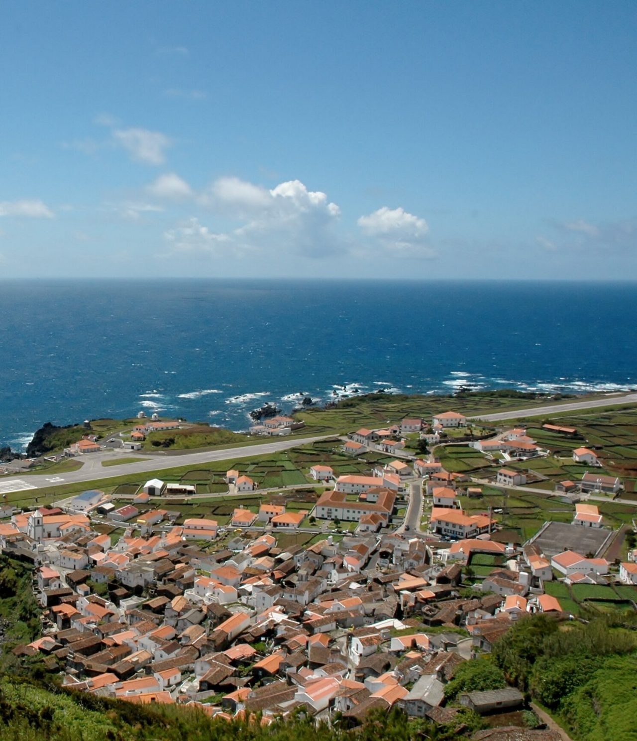 Luftaufnahme der Insel Corvo, mit ihrer Landebahn, malerischem Dorf und natürlichem Pool, umgeben vom tiefblauen Meer