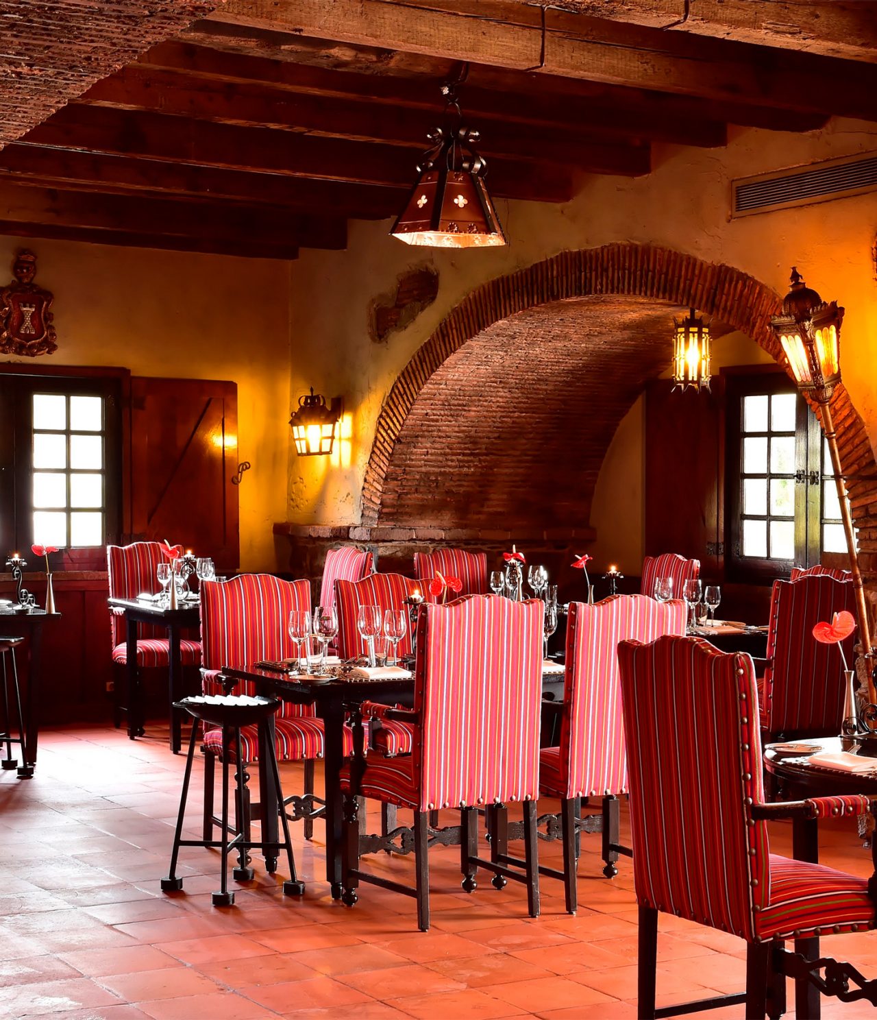 Das Restaurant Taverna Grill im 5-Sterne-Hotel auf Madeira hat einen großen Raum mit roten Stühlen, Tischen und Lampen