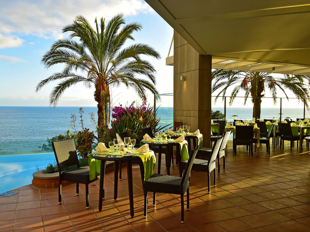 Das Restaurant The Deck im 4-Sterne-Hotel am Meer in Funchal hat mehrere Tische mit Blick auf den Pool und das Meer