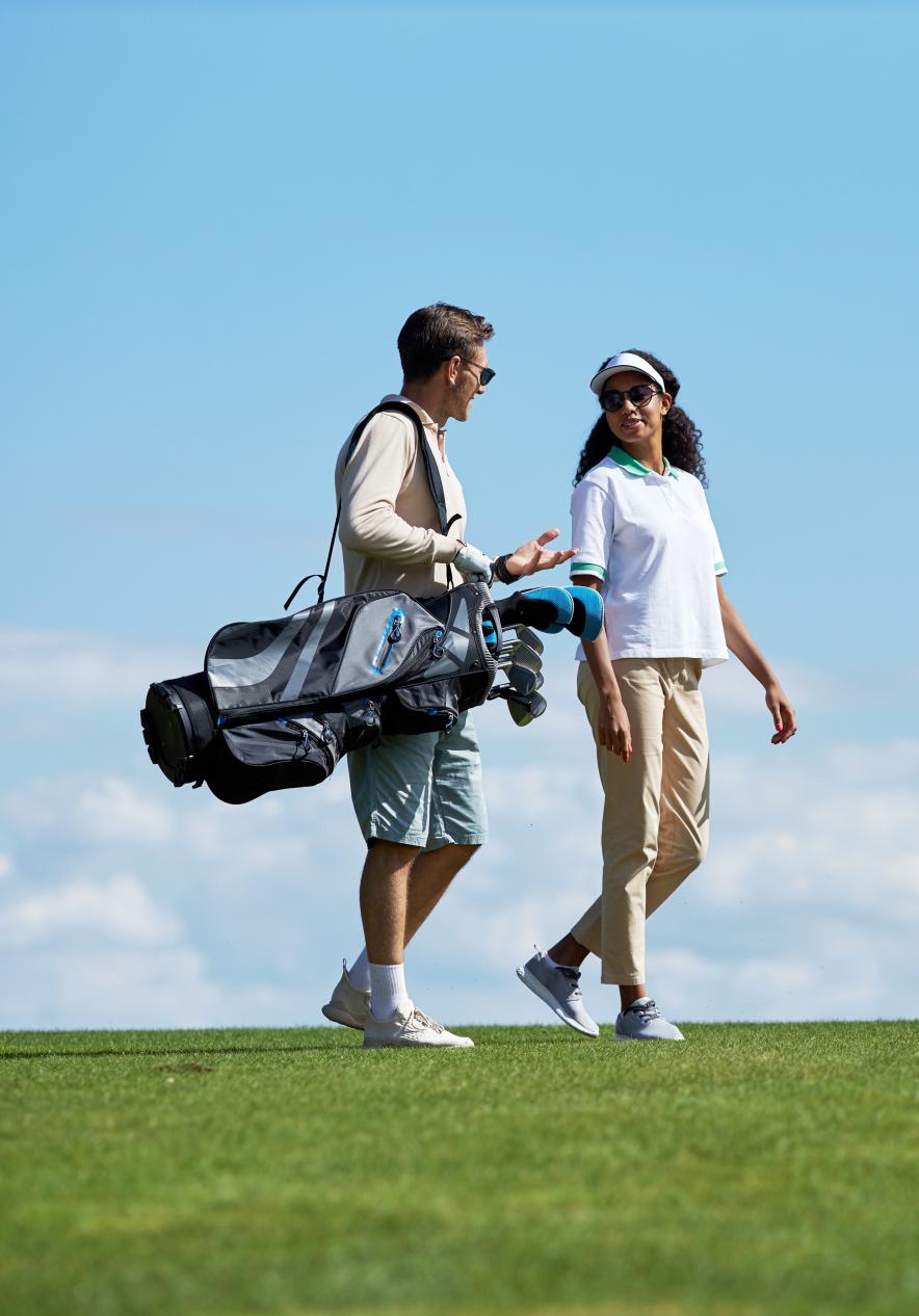 Paar mit Golfschlägern auf einem Golfplatz in Porto Santo bei blauem Himmel