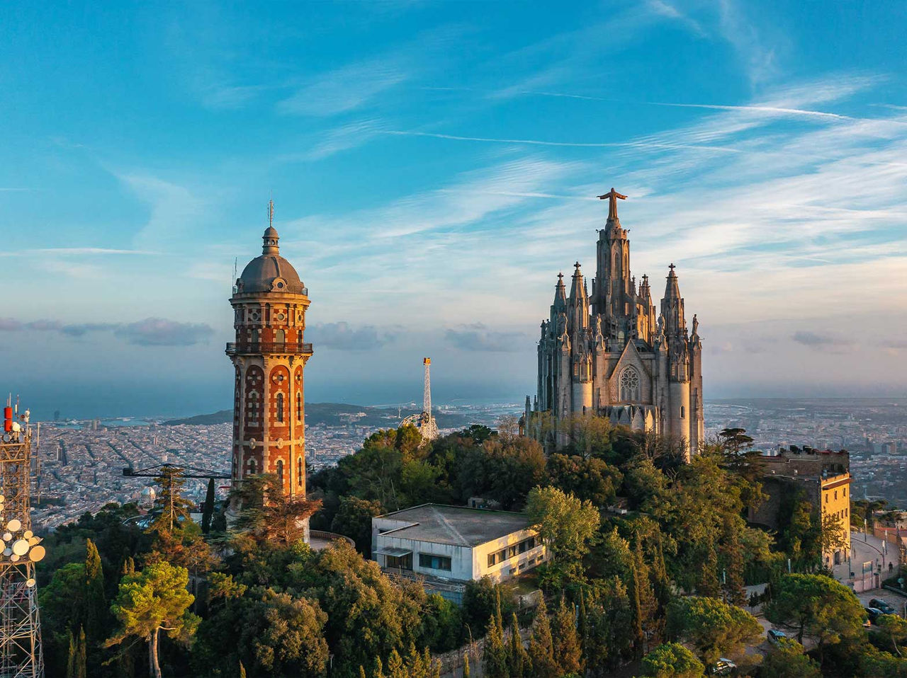 Blick auf den Tempel des Heiligen Herzens Jesu auf dem Tibidabo umgeben von Vegetation mit der Stadt Barcelona im Hintergrund