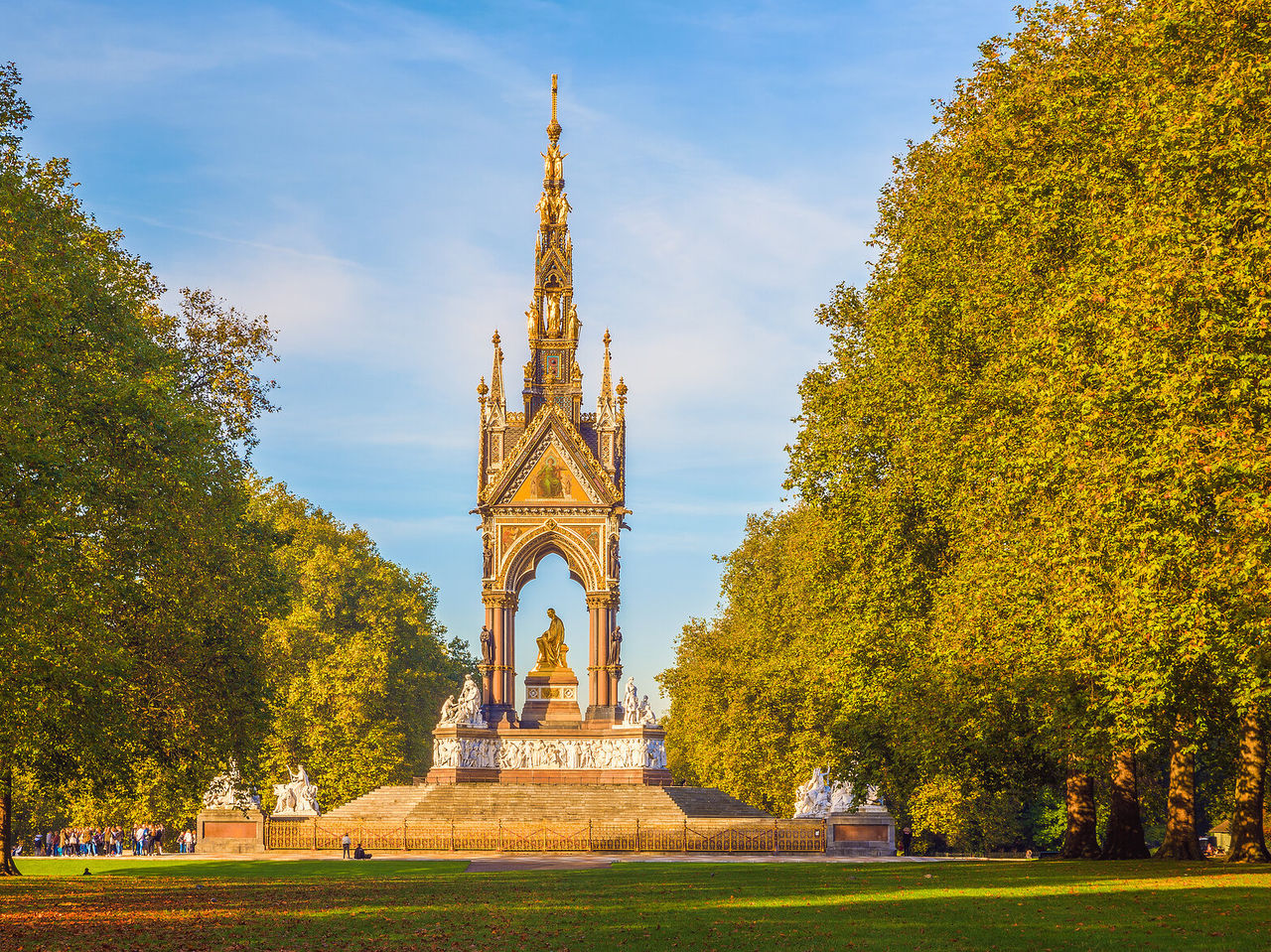 Blick von einem Park auf das ikonische Albert Memorial, mit seiner goldenen Zentralstatue und skulptierten Details