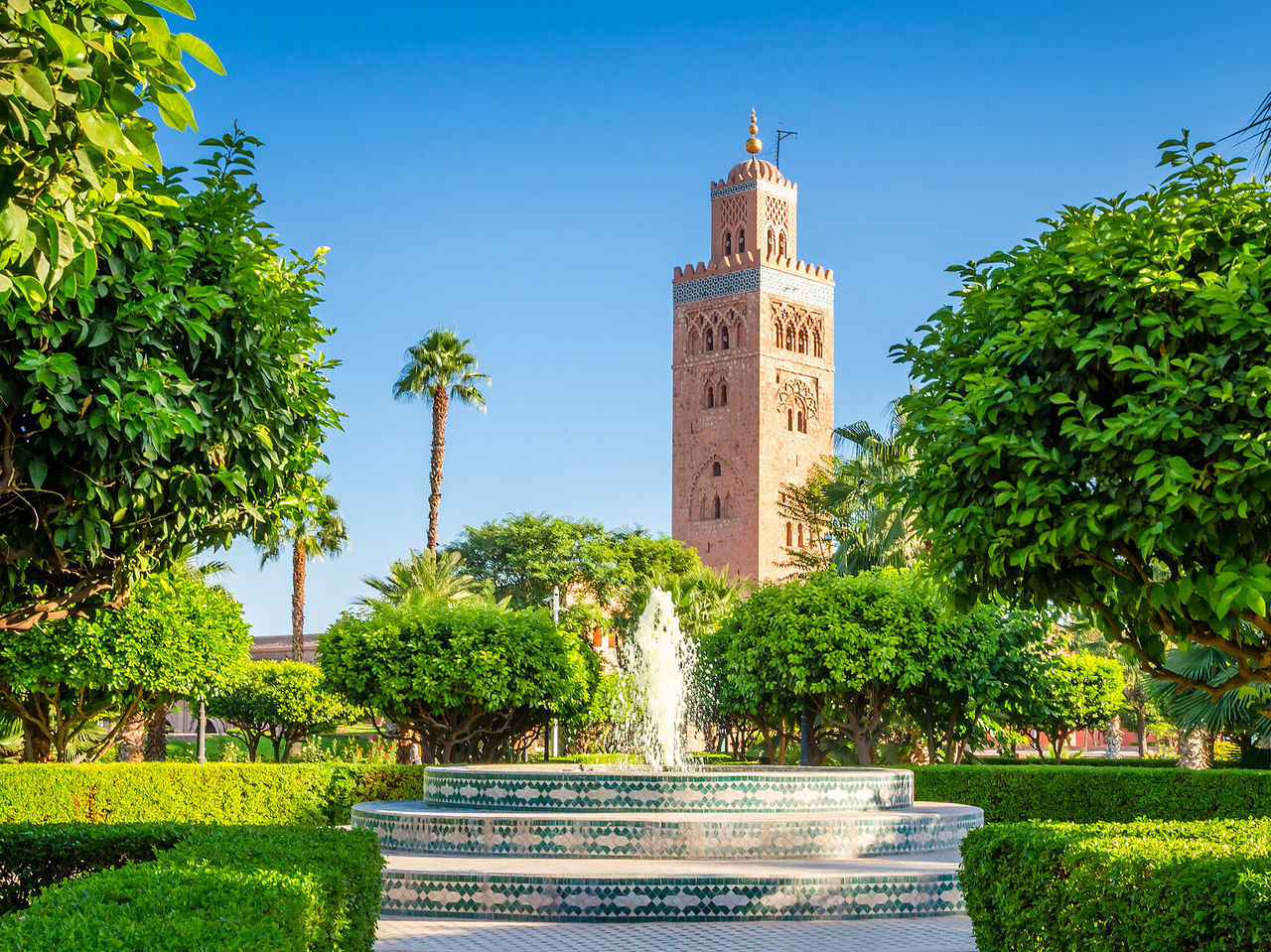  View of the Koutoubia Mosque, historical landmark, surrounded by trees and a typical Moroccan fountain