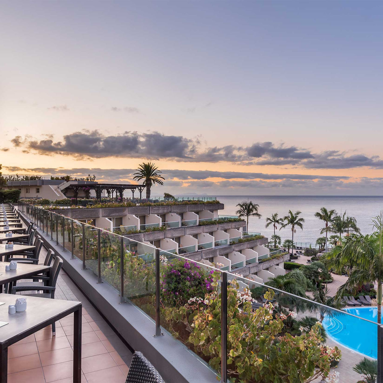 Terrace of a 5-star hotel in Madeira, overlooking balconies with buildings, the pool, and the sea