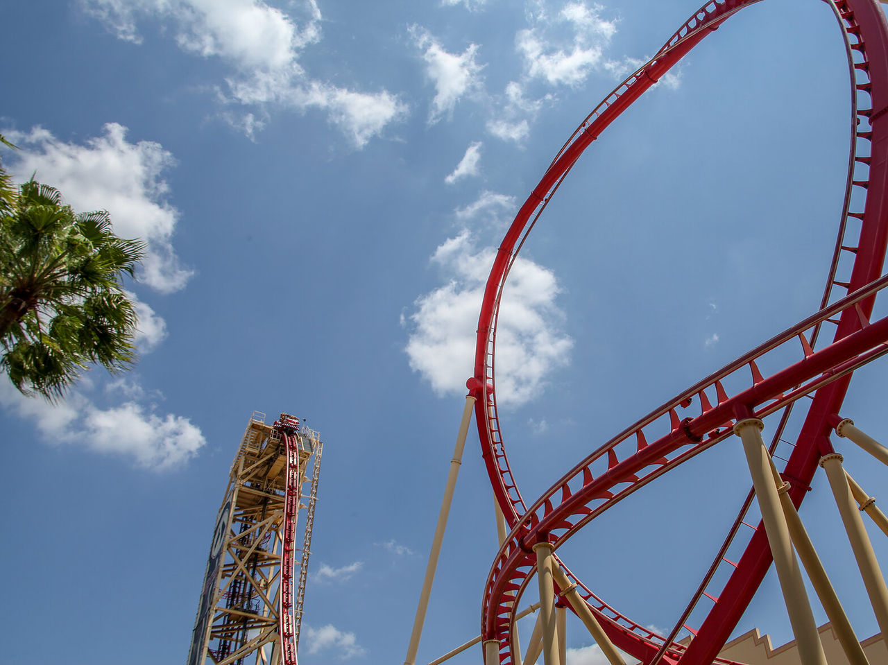 Roller coaster with sharp turns, against a blue sky with few clouds