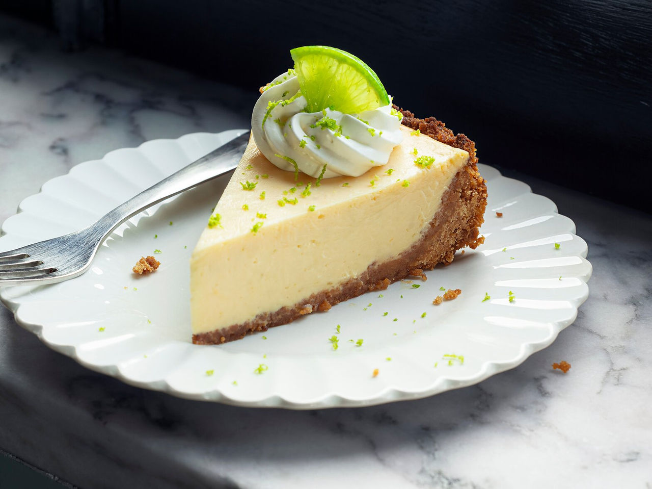 Slice of lemon pie, with a crunchy crust and a creamy filling topped with lemon zest