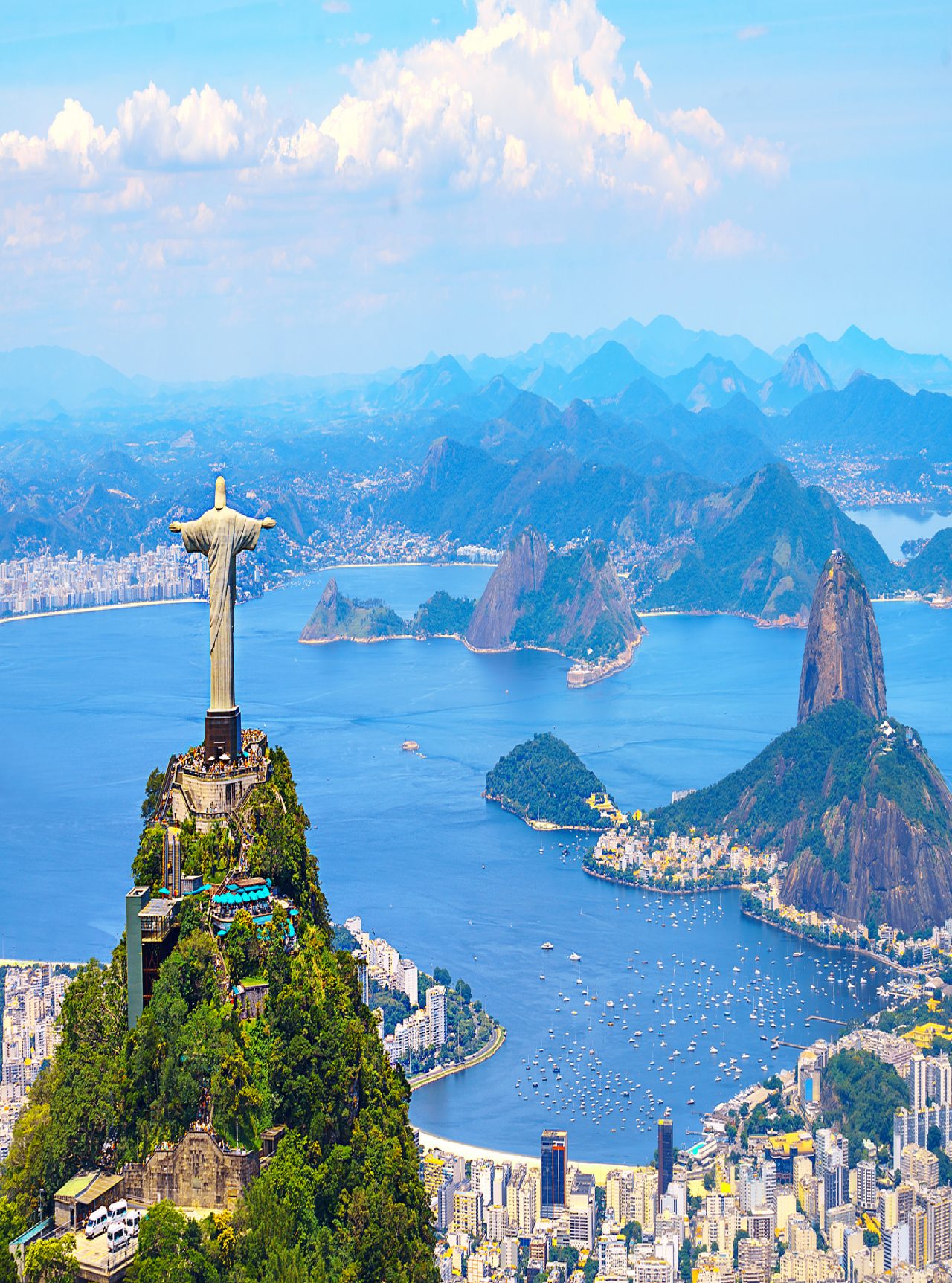 Iconic statue of Christ the Redeemer in Rio de Janeiro, with the city, ocean, and beach in the background