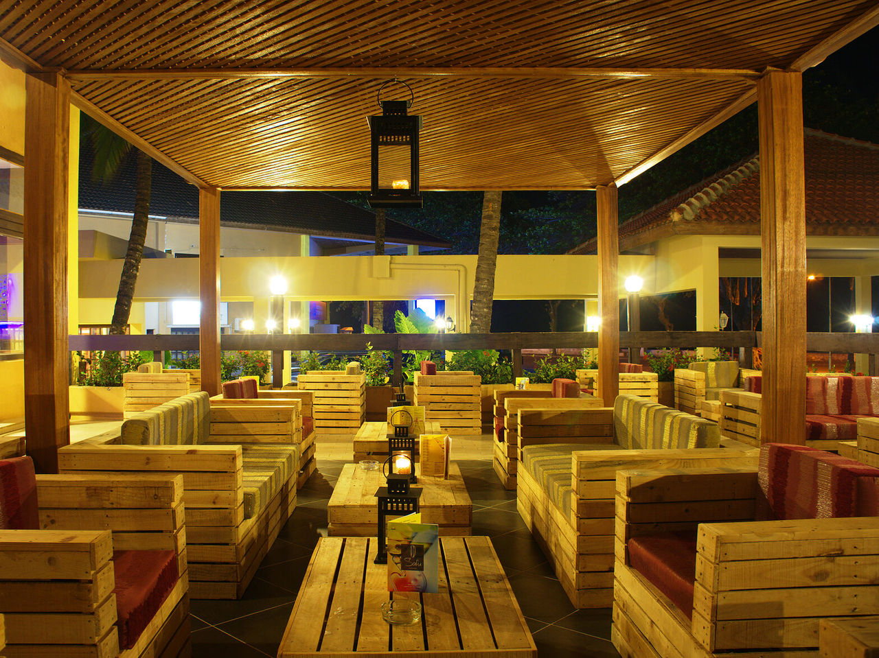 El bar Safu, del Hotel 4 Estrelas en São Tomé, tiene varias mesas con sofás de madera y cojines coloridos