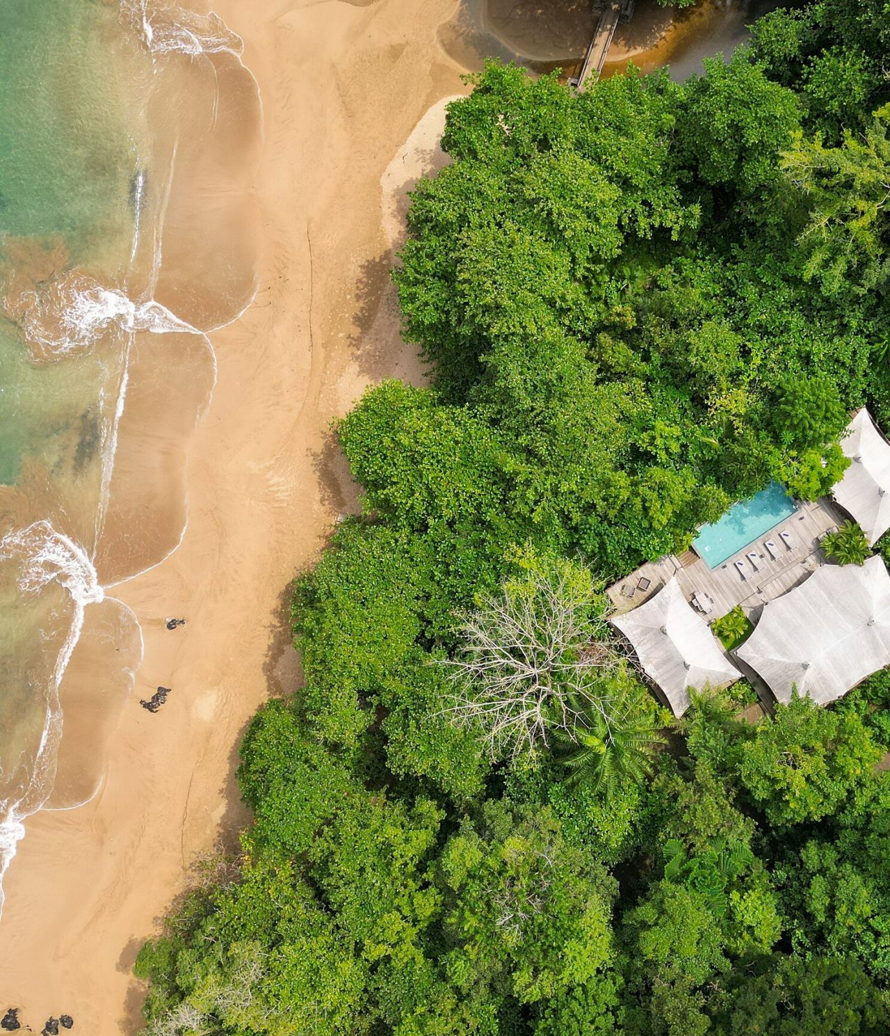 Vue aérienne de l'île de São Tomé et Príncipe, bâtiment avec piscine et une plage de sable blanc avec des eaux cristallines