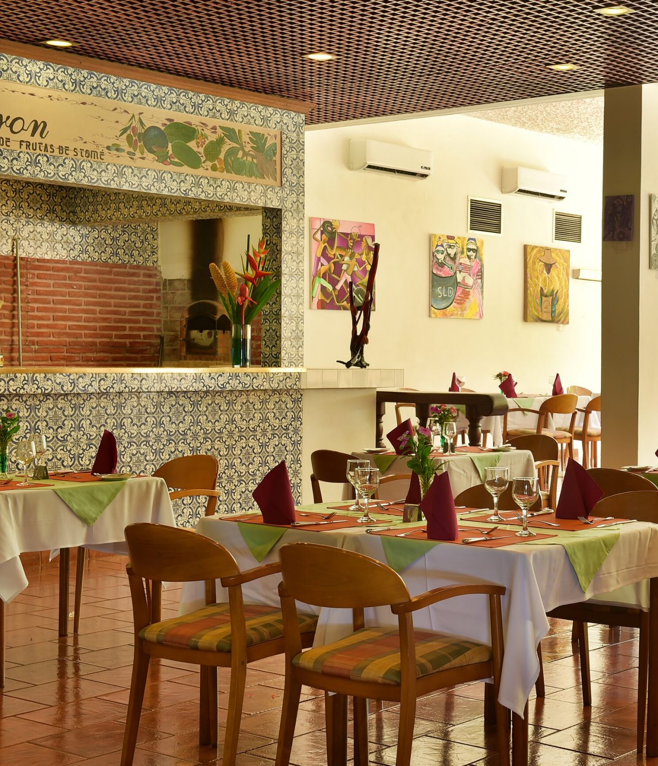 Le restaurant Le Baron, de l'hôtel 4 étoiles à São Tomé, a des tables dressées avec chaises en bois