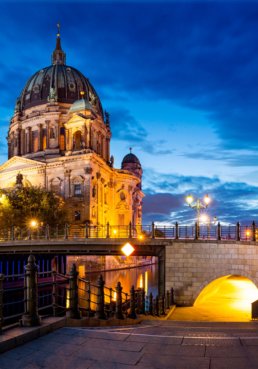 Cathédrale de Berlin illuminée à la tombée de la nuit, avec un pont et des bâtiments modernes à côté