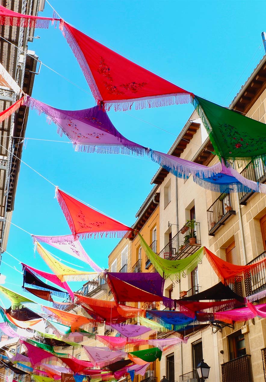 Rue avec des voiles aux fils colorés accrochés aux fenêtres et balcons des bâtiments de chaque côté