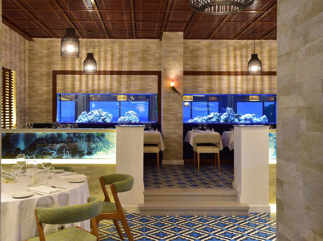 Le restaurant Sul de l’hôtel 5 étoiles en Algarve a des aquariums, des lampes au plafond et des chaises rembourrées