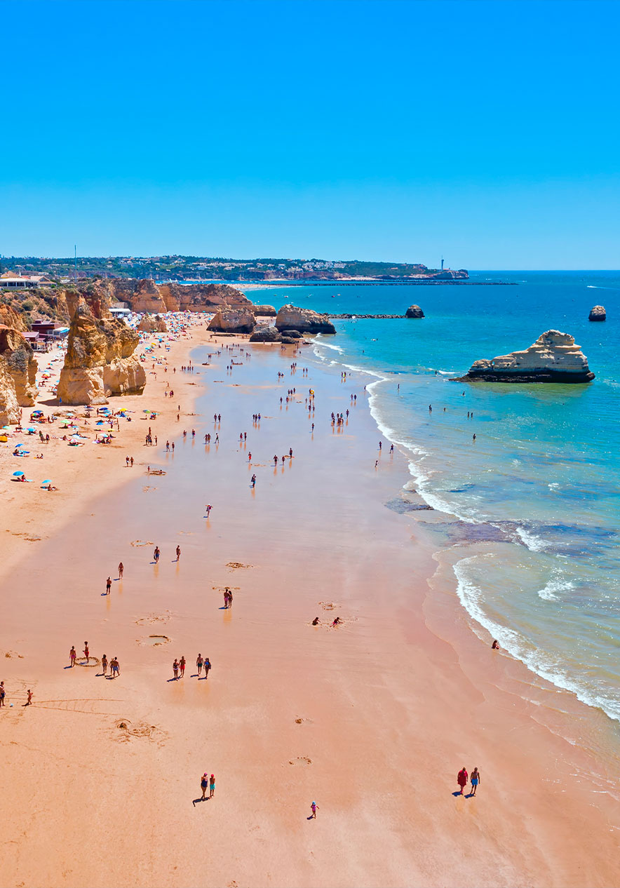 Visitez la Praia da Rocha avec ses rochers sur le sable qui touchent l'eau bleue de l'Algarve