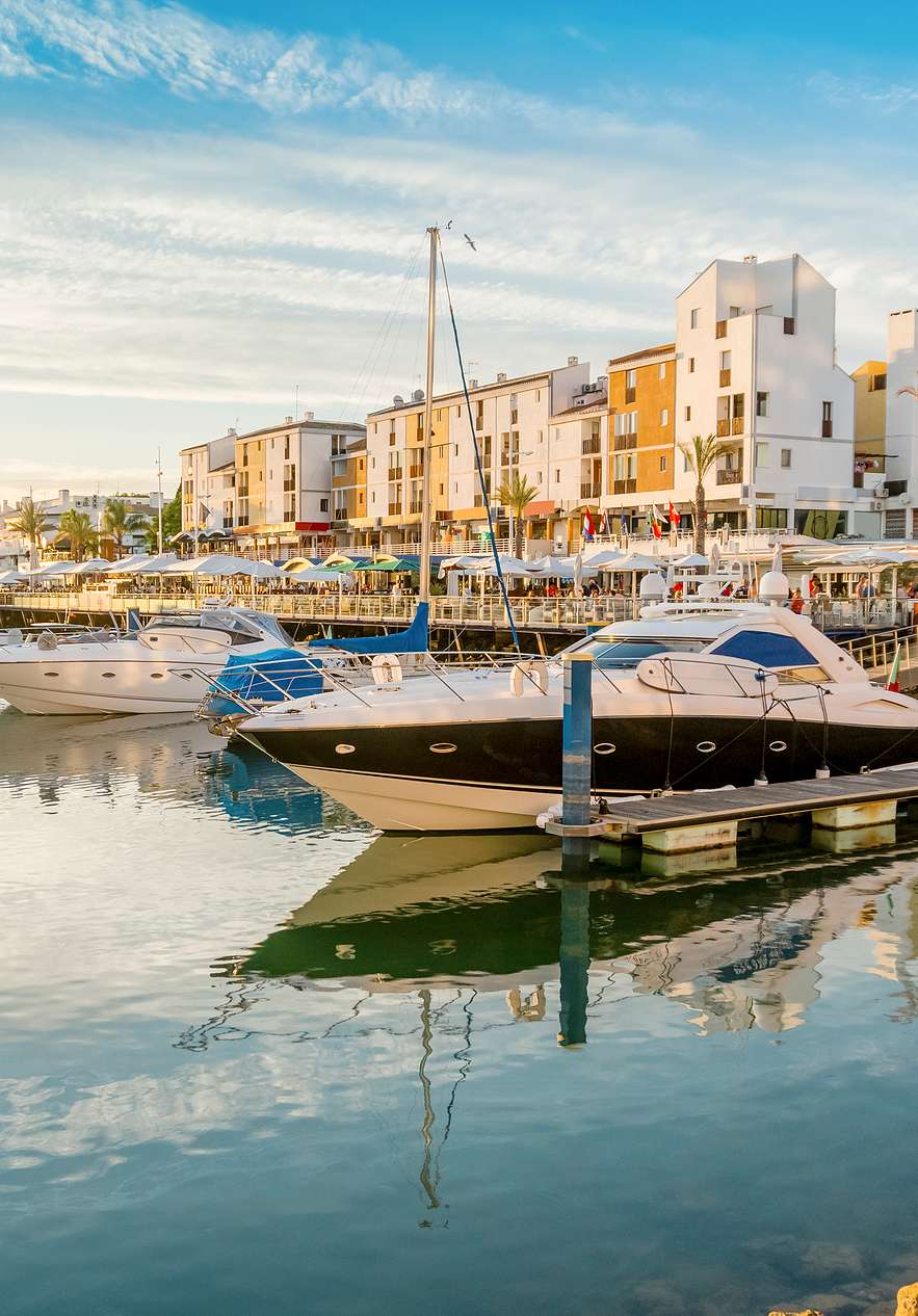 Marina de Vilamoura au coucher du soleil, avec des bateaux de différentes tailles et styles et une eau calme