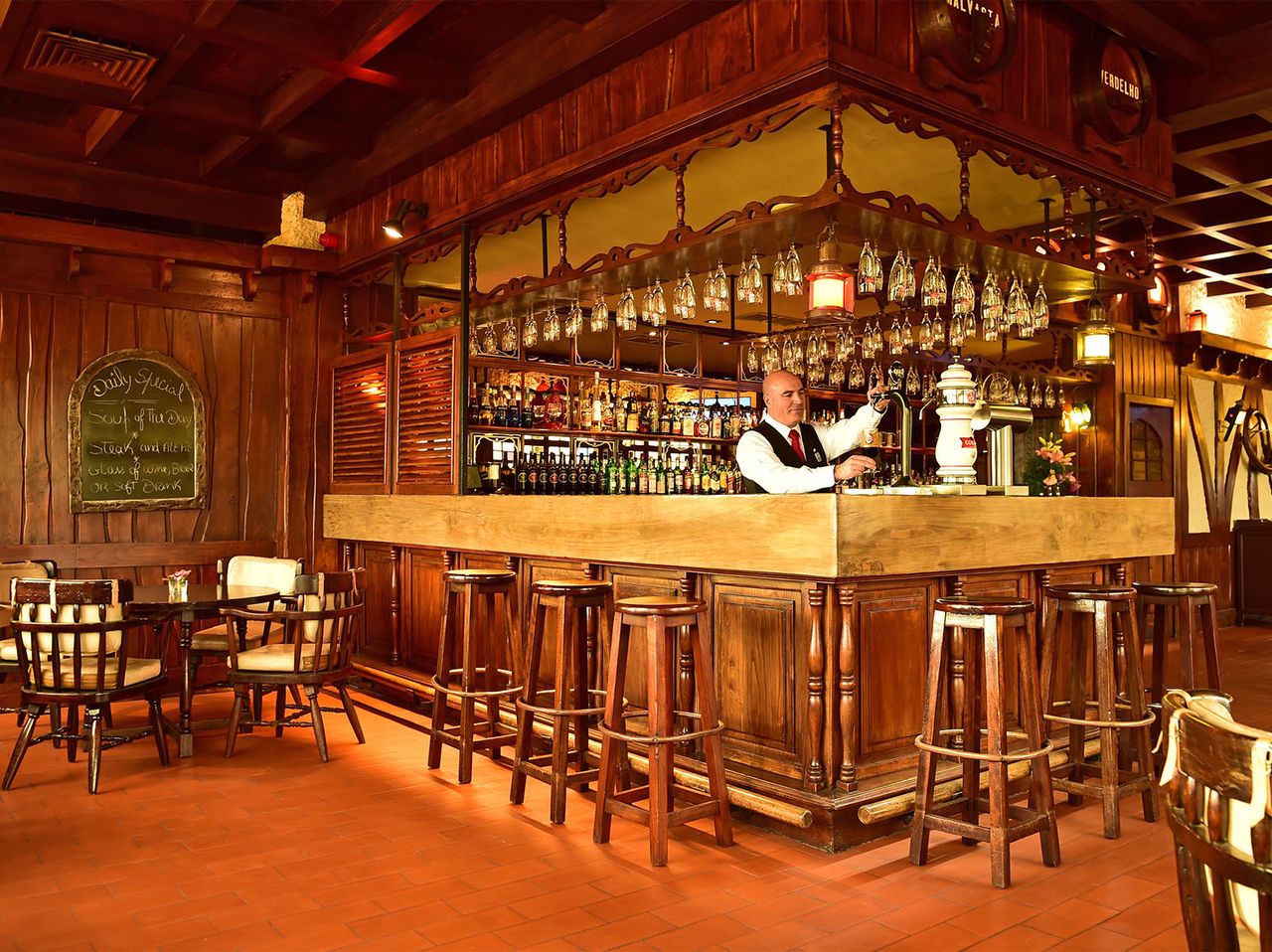 Le bar The Pub de l’hôtel 5 étoiles à Madère a un comptoir entouré de bancs hauts avec plusieurs boissons
