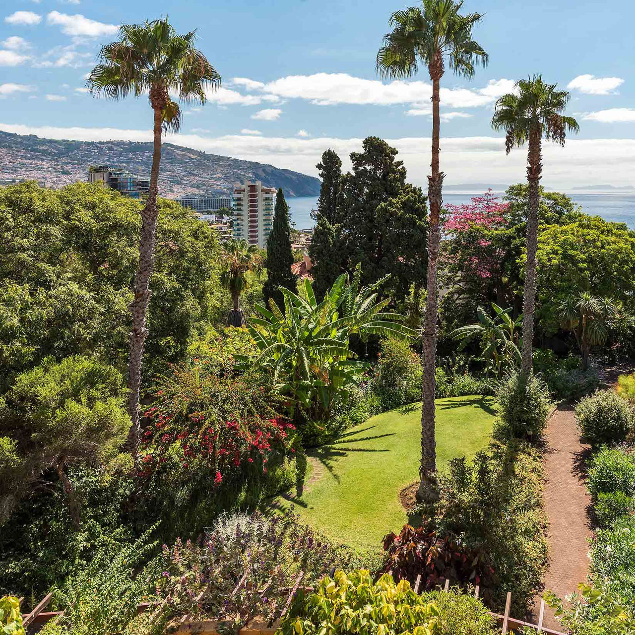Jardin avec diverses plantes tropicales, vue sur la mer et colline au Pestana Village, Hôtel Romantique à Funchal, Madère