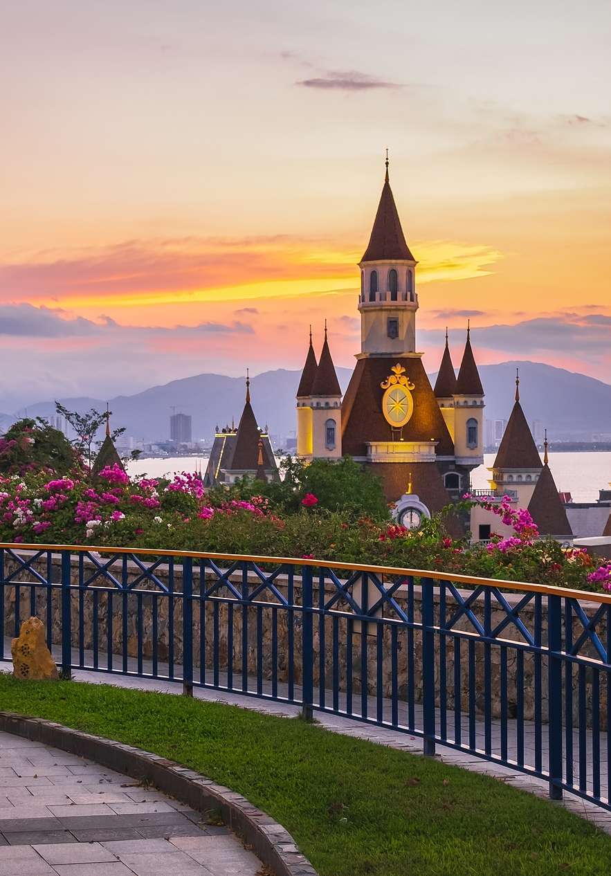 Vue panoramique d'un château dans un parc à thème Disney à Orlando, avec un lac et des montagnes en arrière-plan