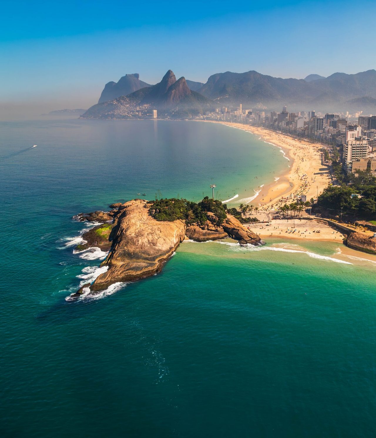 Vue aérienne de Rio de Janeiro, avec des montagnes en arrière-plan, plage de sable blanc et mer bleue turquoise