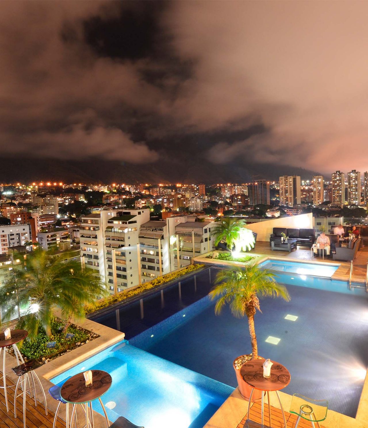 Le bar Lounge Vip 19 de l’hôtel à Caracas a une piscine, des palmiers et une vue panoramique sur la ville