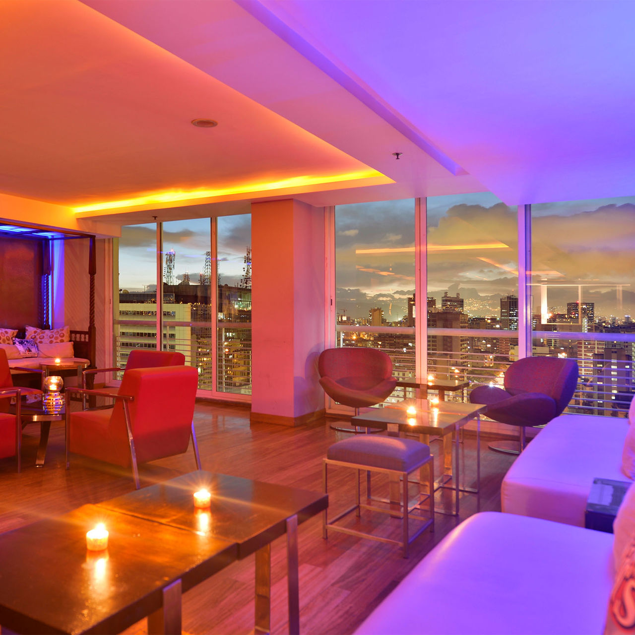 Bar du Pestana Caracas avec vue panoramique de la ville au coucher du soleil, espace moderne avec canapés