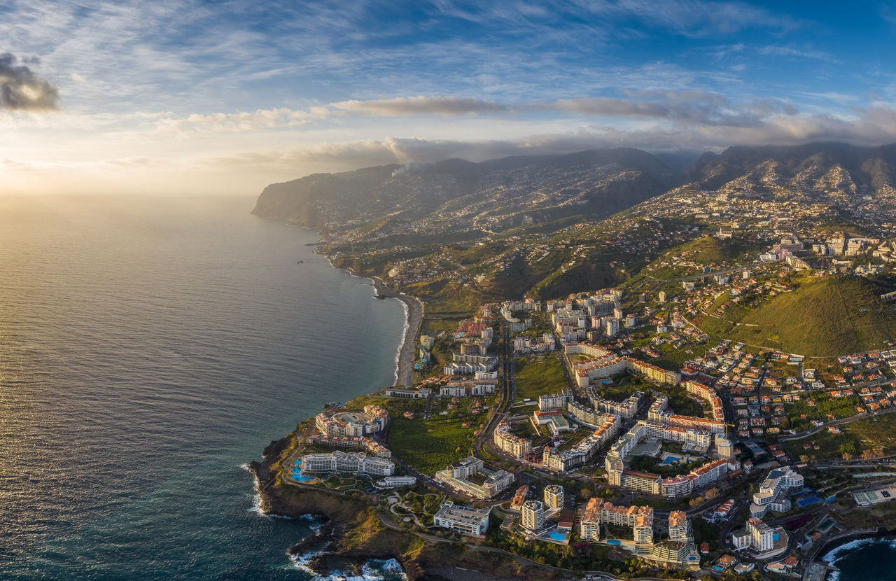 Luchtzicht op de stad Funchal op Madeira, met een haven met boten, dichtbebouwde stedelijke gebieden en bergen op de achtergrond