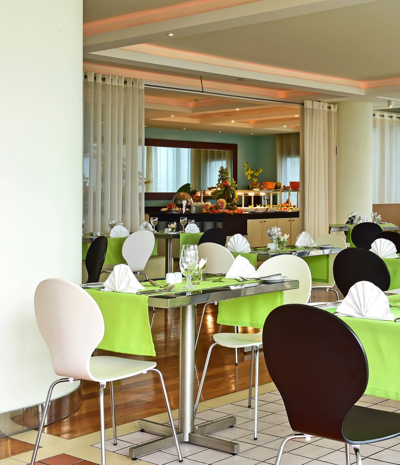 Het restaurant Breezes, van het hotel aan zee in Funchal, heeft verschillende tafels met groene tafellakens en een buffet