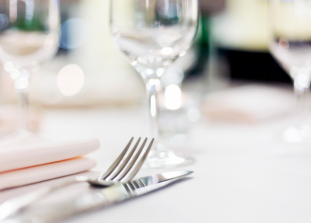 Elegante tafel gedekt met zilveren bestek, stoffen servet en glaswerk, in een goed verlichte omgeving