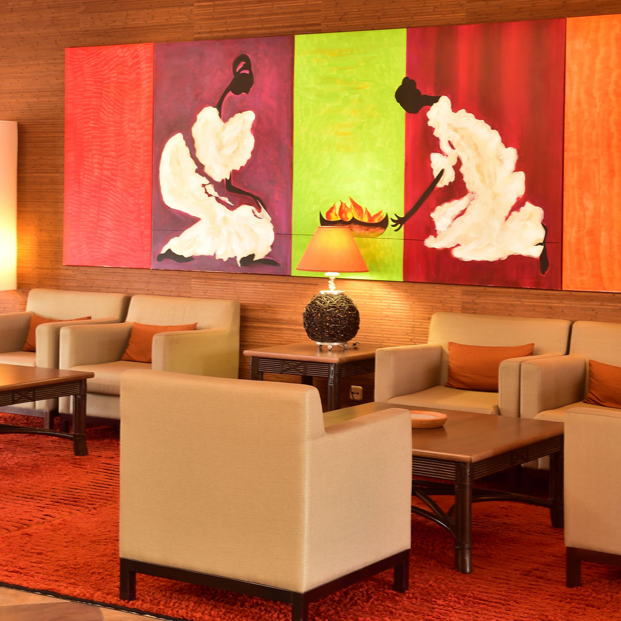 Lounge da receção com três cadeirões, mesa de cabeceira com candeeiro, e uma quadro pintado pendurado na parede