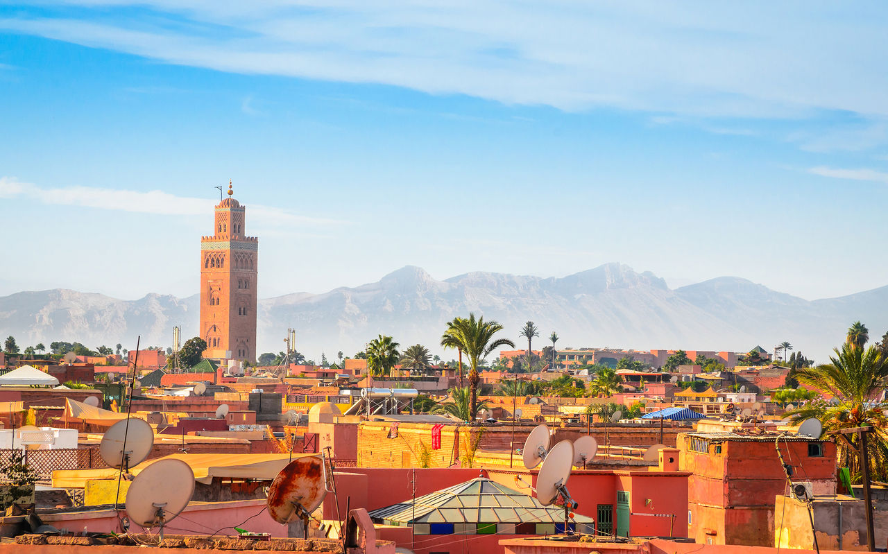 Aerial view of the historic center of Marrakech, with the Koutoubia Mosque tower and the surrounding mountains